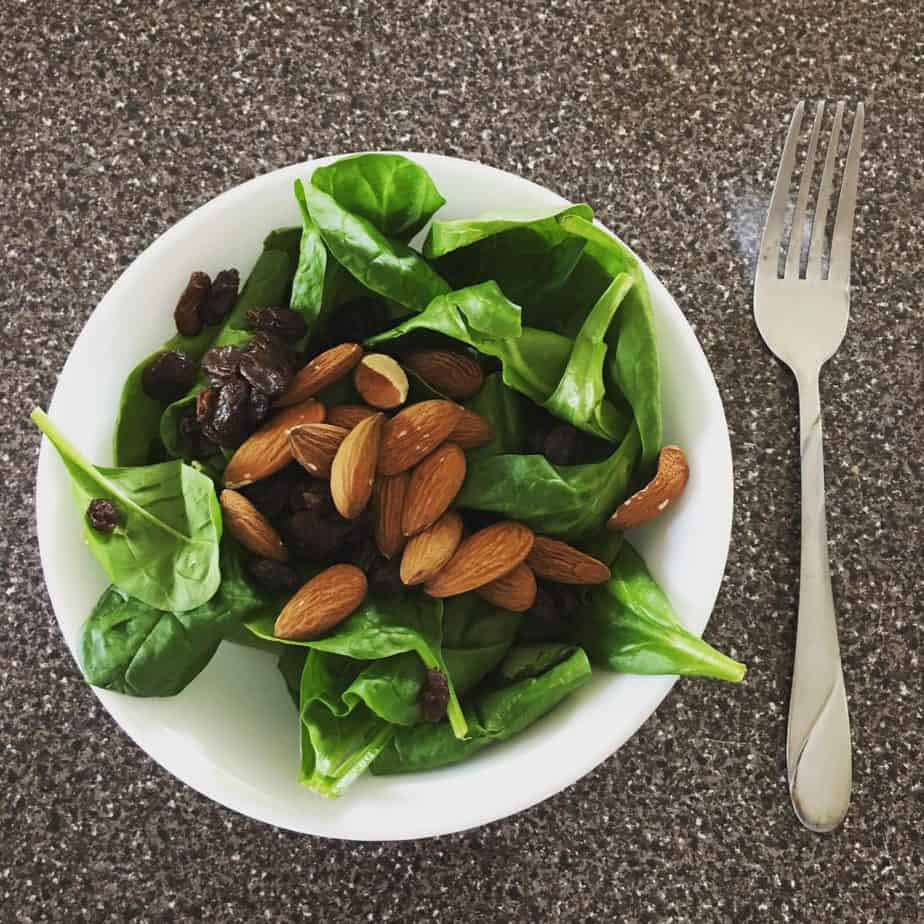 a bowl full of spinach, almonds, and raisins is an easy meal idea for better nutrition during pregnancy