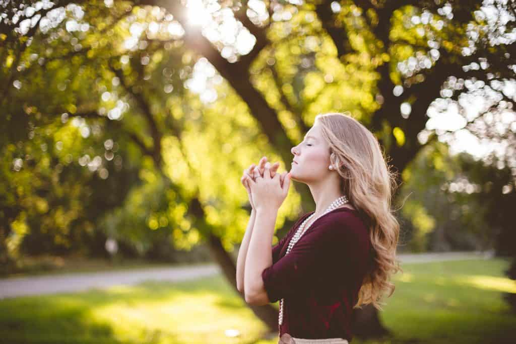 blonde woman praying outside