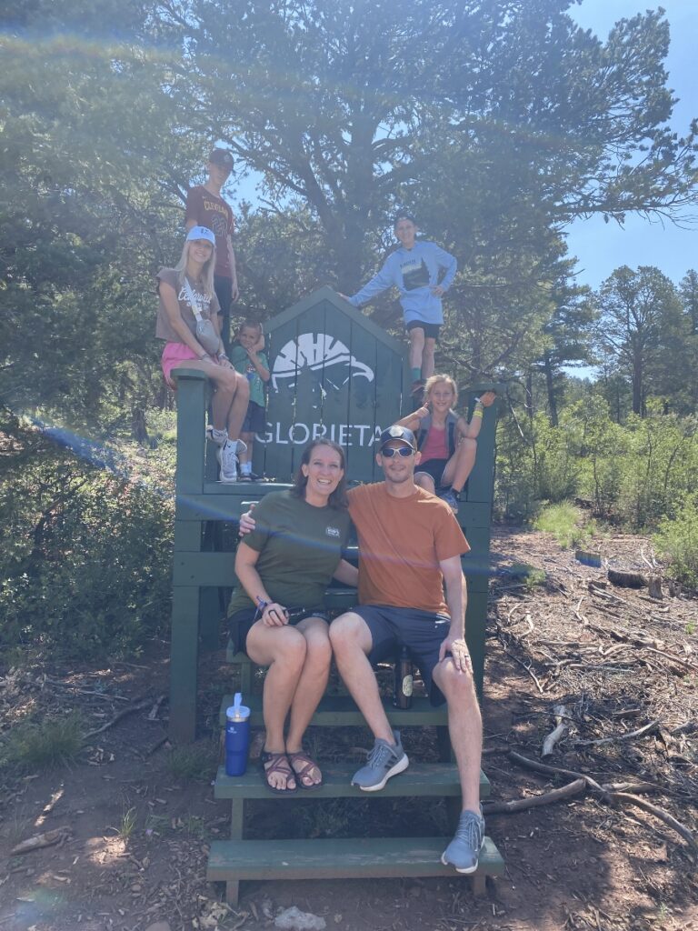 family photo by the big chair at Glorieta Adventure Camp in New Mexico