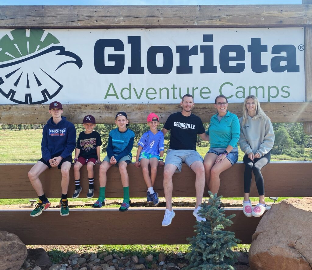 family photo by the welcome sign at Glorieta Adventure Camp in New Mexico